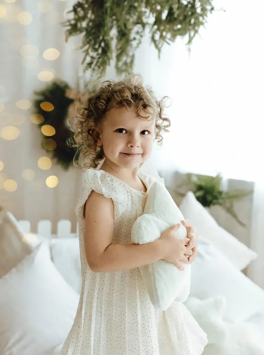 Weihnachts-Mini – Mädchen mit Kuscheltier vor Lichterkranz